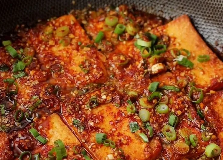 Close-up of Korean braised tofu in a savory sauce with vegetables.