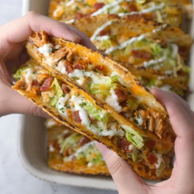 Baked chicken bacon ranch tacos on a plate garnished with herbs