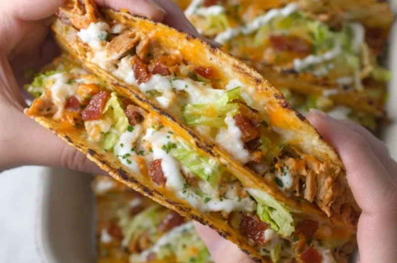 Baked chicken bacon ranch tacos on a plate garnished with herbs