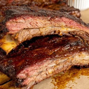 Smoky tender beef ribs on a barbecue grill, ready to serve.