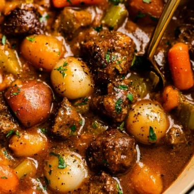 Delicious beef stew simmering in a pot with fresh vegetables and herbs