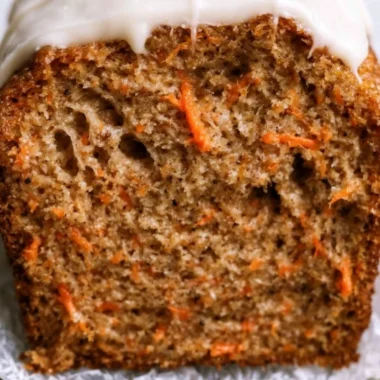 Cozy carrot cake loaf served on a rustic plate with frosting and decorative carrots