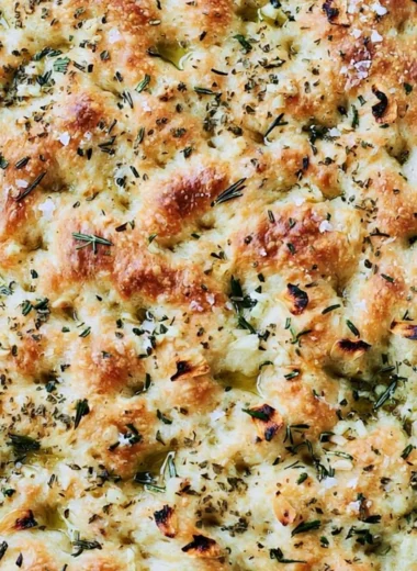 Delicious garlic rosemary focaccia bread garnished with fresh herbs.