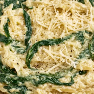Creamy garlic spinach orzo dish served in a bowl, garnished with parsley.