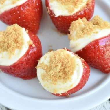 Easy no-bake strawberry cheesecake bites on a white plate topped with fresh strawberries.