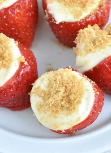 Easy no-bake strawberry cheesecake bites on a white plate topped with fresh strawberries.