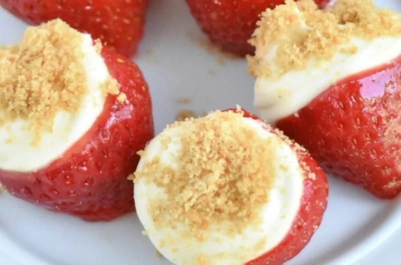 Easy no-bake strawberry cheesecake bites on a white plate topped with fresh strawberries.