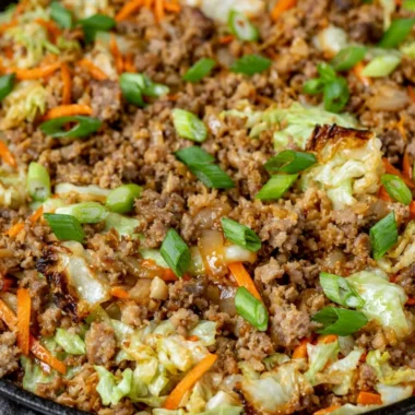 Bowl filled with egg roll ingredients, featuring cabbage, carrots, and protein.