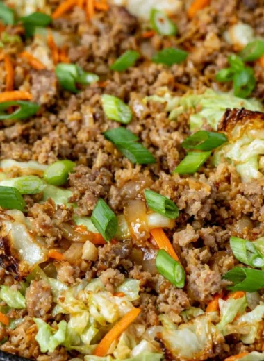 Bowl filled with egg roll ingredients, featuring cabbage, carrots, and protein.