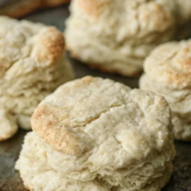 Freshly baked homemade buttery biscuits on a wooden table.