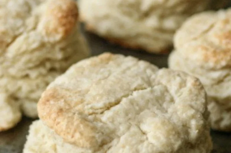 Freshly baked homemade buttery biscuits on a wooden table.