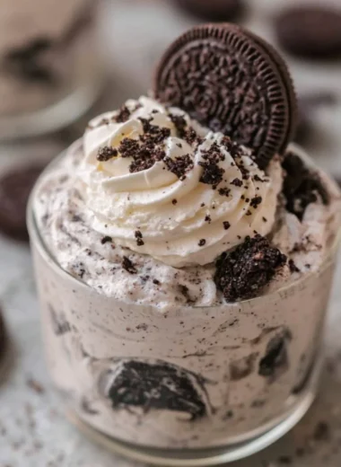 No bake Oreo cheesecake cups topped with crushed Oreos and whipped cream.
