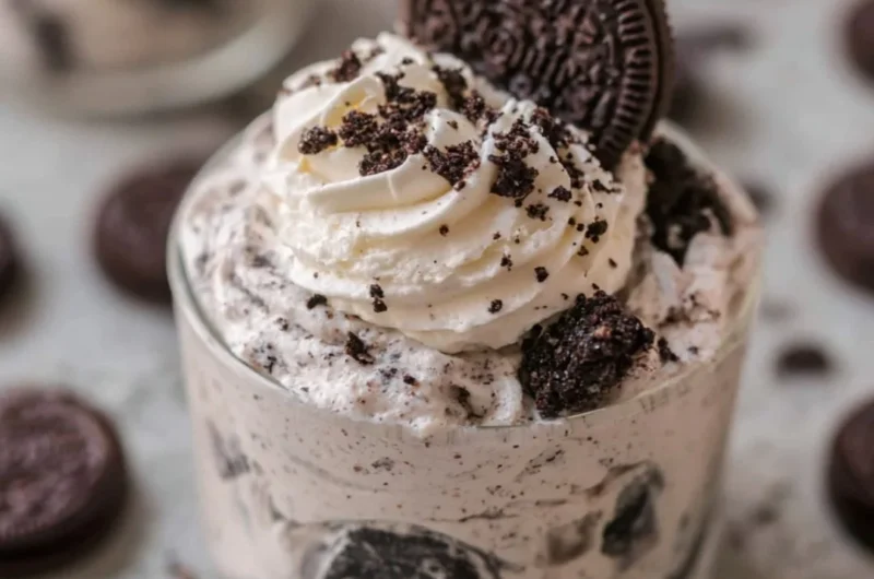 No bake Oreo cheesecake cups topped with crushed Oreos and whipped cream.