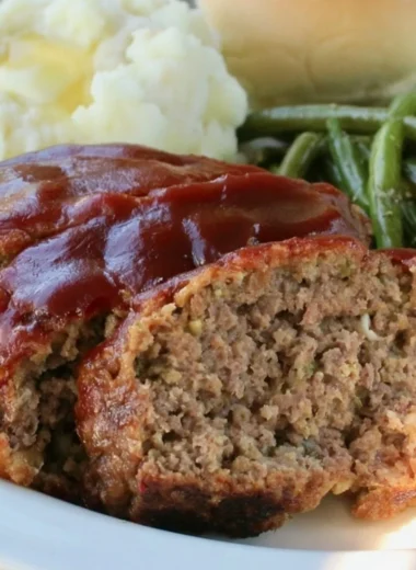 Old fashioned meatloaf baked in a loaf pan, served with mashed potatoes and green beans.