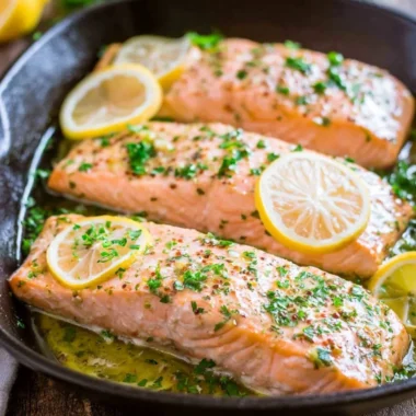 Delicious oven roasted salmon served with herbs and lemon slices.