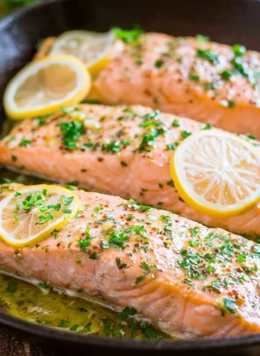 Delicious oven roasted salmon served with herbs and lemon slices.
