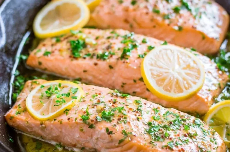 Delicious oven roasted salmon served with herbs and lemon slices.
