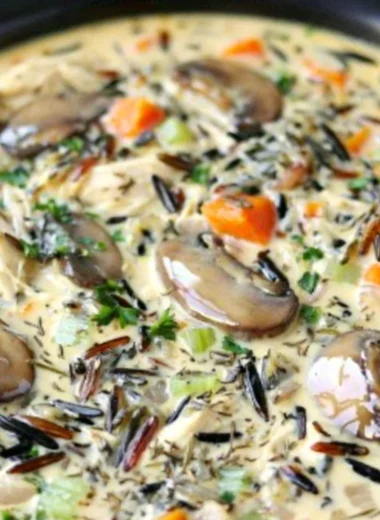 Bowl of slow cooker creamy chicken wild rice soup garnished with herbs